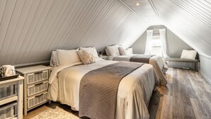 Ein gemütliches Schlafzimmer im Dachgeschoss mit zwei Betten, einer Bank und einem kleinen Tisch mit einem Korb.