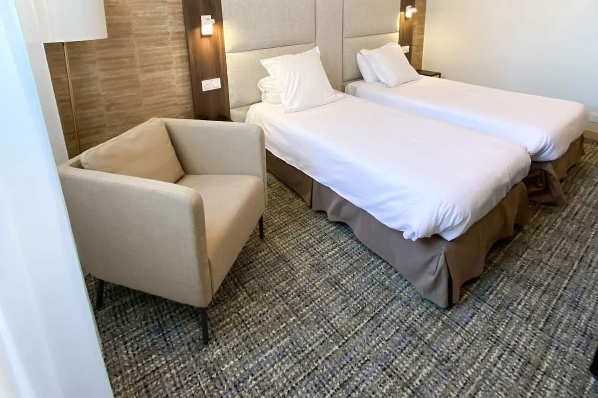Een hotelkamer met een bed, twee nachtkastjes, een stoel en een lamp.