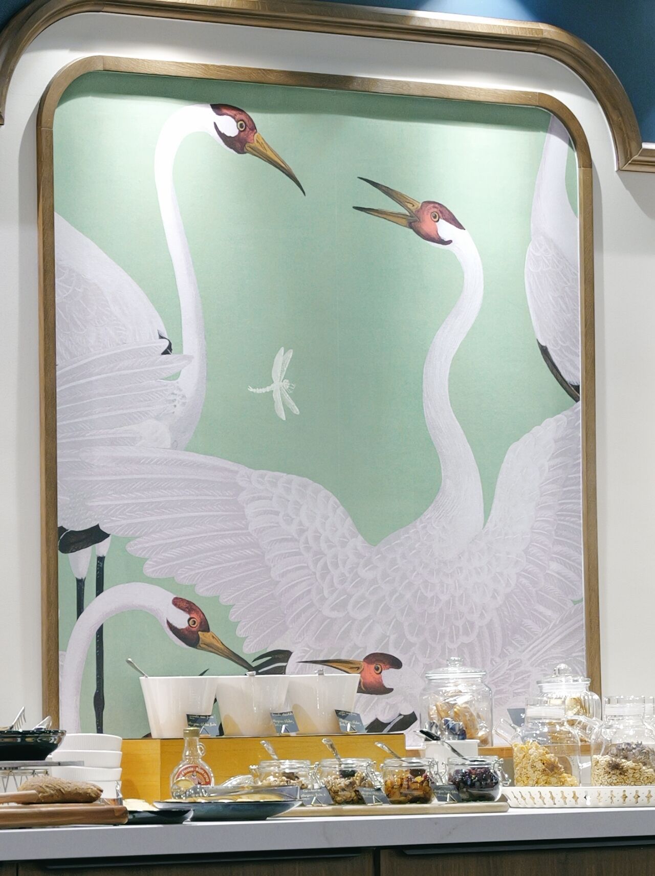 Een buffetgedeelte met een decoratieve muur waarop vogels en een libelle afgebeeld zijn.