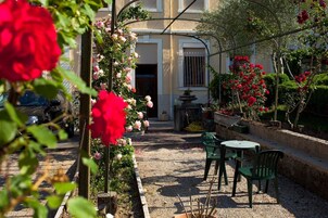 A garden patio with a pergola, seating area, and a fountain.