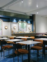Un restaurante con mesas y sillas, una barra con productos alimenticios y una pared con un mural.