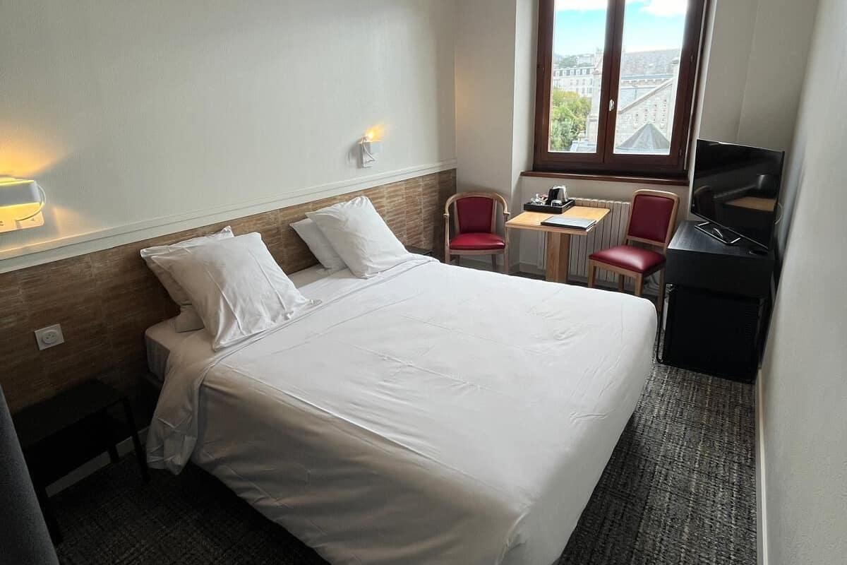 Hotelkamer met een groot bed, een bureau, een stoel, een televisie en een raam met uitzicht op de stad.