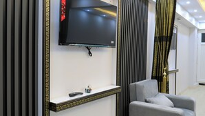A modern living room with a mounted TV, a grey sofa, and a decorative wall panel. - Istanbul Hotel & Guesthouse  (Istanbul)