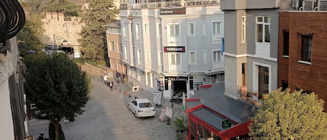 A street view with a row of buildings, including a terrace restaurant and a villa sofa.