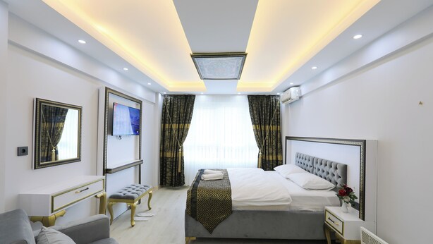 A modern hotel room with a bed, a sofa, a desk, and a TV. - Istanbul Hotel & Guesthouse  (Istanbul)