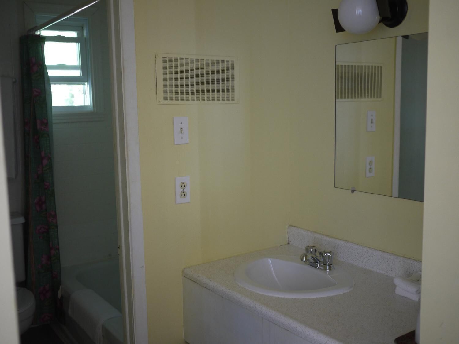 Un baño con lavabo, espejo y ventilación.