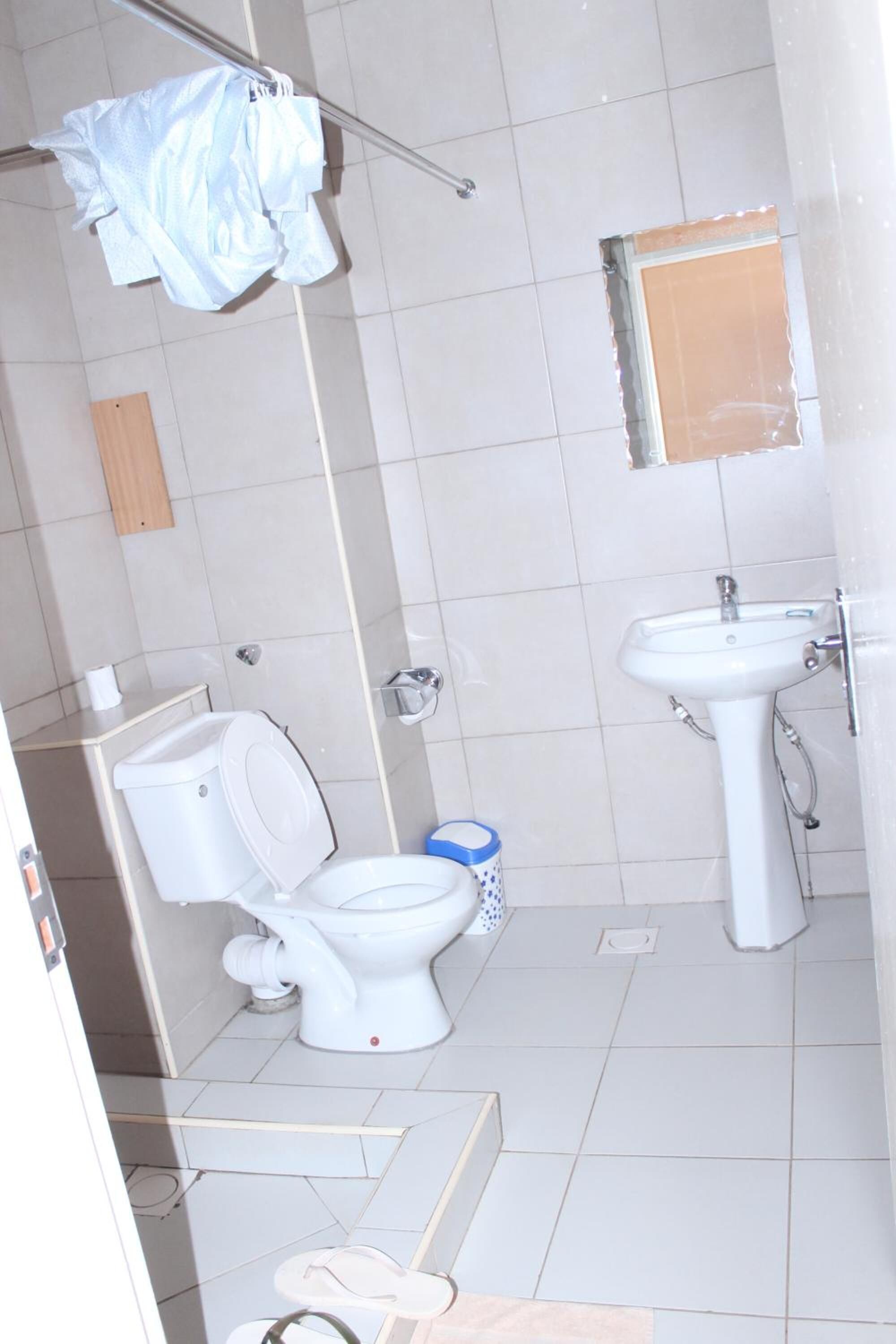 A bathroom with a toilet, sink, and shower area.