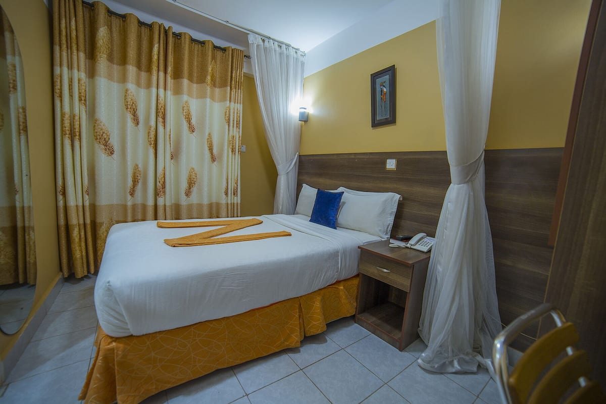 Una habitación de hotel con una cama, una mesita de noche, un teléfono y una silla.