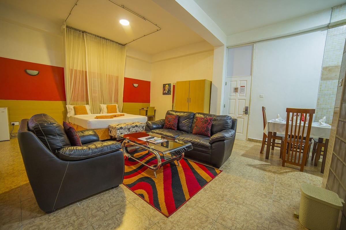 Una sala de estar con una cama, dos sofás, una mesa de centro y un comedor.