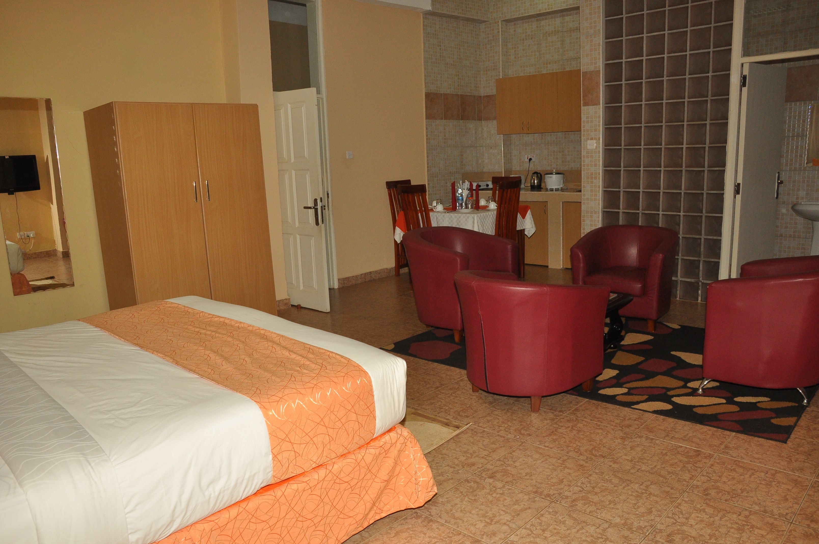 Habitación de hotel con cama, escritorio, silla y una kitchenette pequeña.