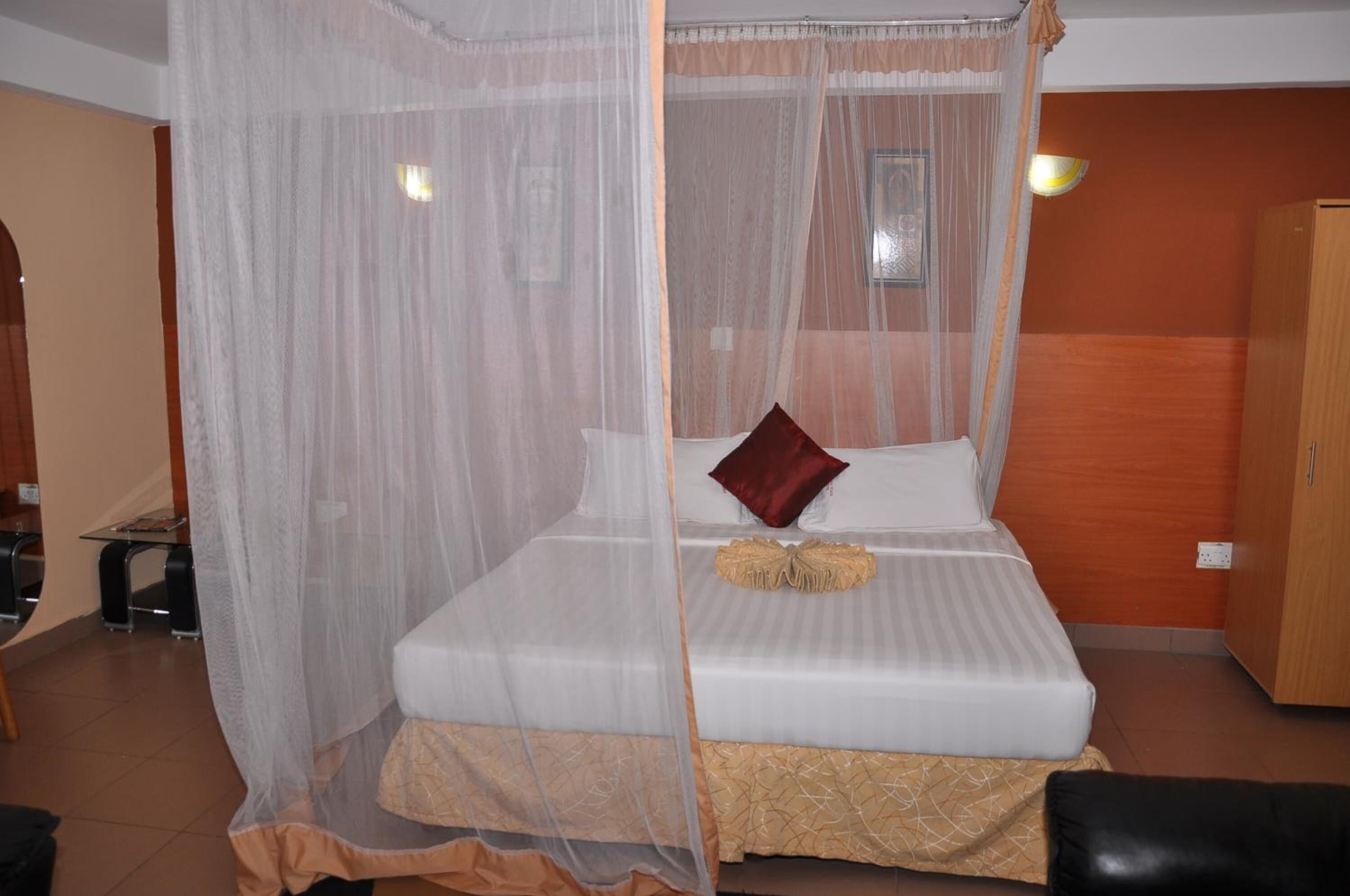A bed with a canopy, a bedside table, a lamp, and a wardrobe.