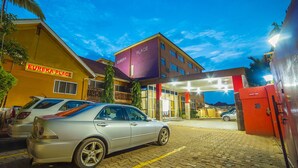 A hotel entrance with a paved driveway, a security point, and a car parked in front. - Eureka Place Hotel (Kampala)