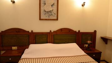 A neatly made bed with a striped bedspread, wooden headboard with green panels, and two bedside tables with lamps.