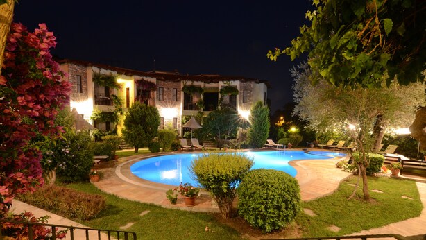 Una piscina circondata da verde curato e un edificio con numerosi balconi.