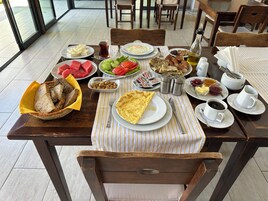 Una mesa de comedor con diversos alimentos para el desayuno, como pan, huevos y verduras.