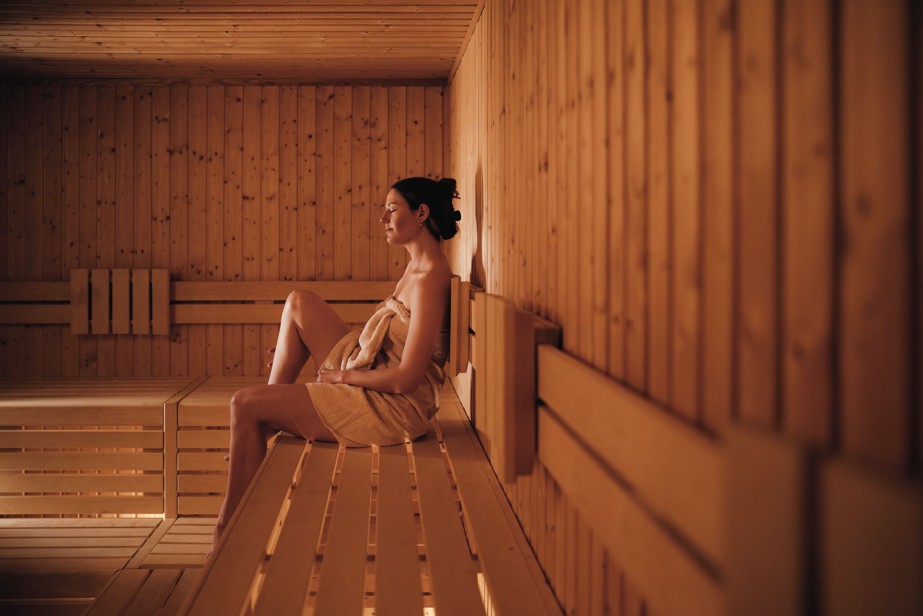 A wooden sauna with benches and a sloped ceiling.