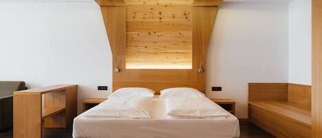 A modern bedroom with a wooden ceiling, a bed with white bedding, a wooden bench, and a small table.