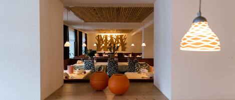 Ein modernes Interieur mit Holzboden, dekorativen Wandmustern und einer Sitzgelegenheit mit gemustertem Sitz.