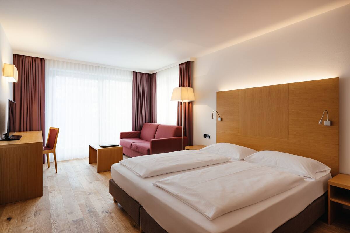 Une chambre d’hôtel avec un grand lit, un bureau, une chaise et un canapé.