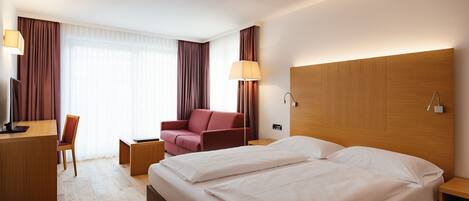 Una habitación de hotel con una cama grande, un escritorio, una silla y un sofá.