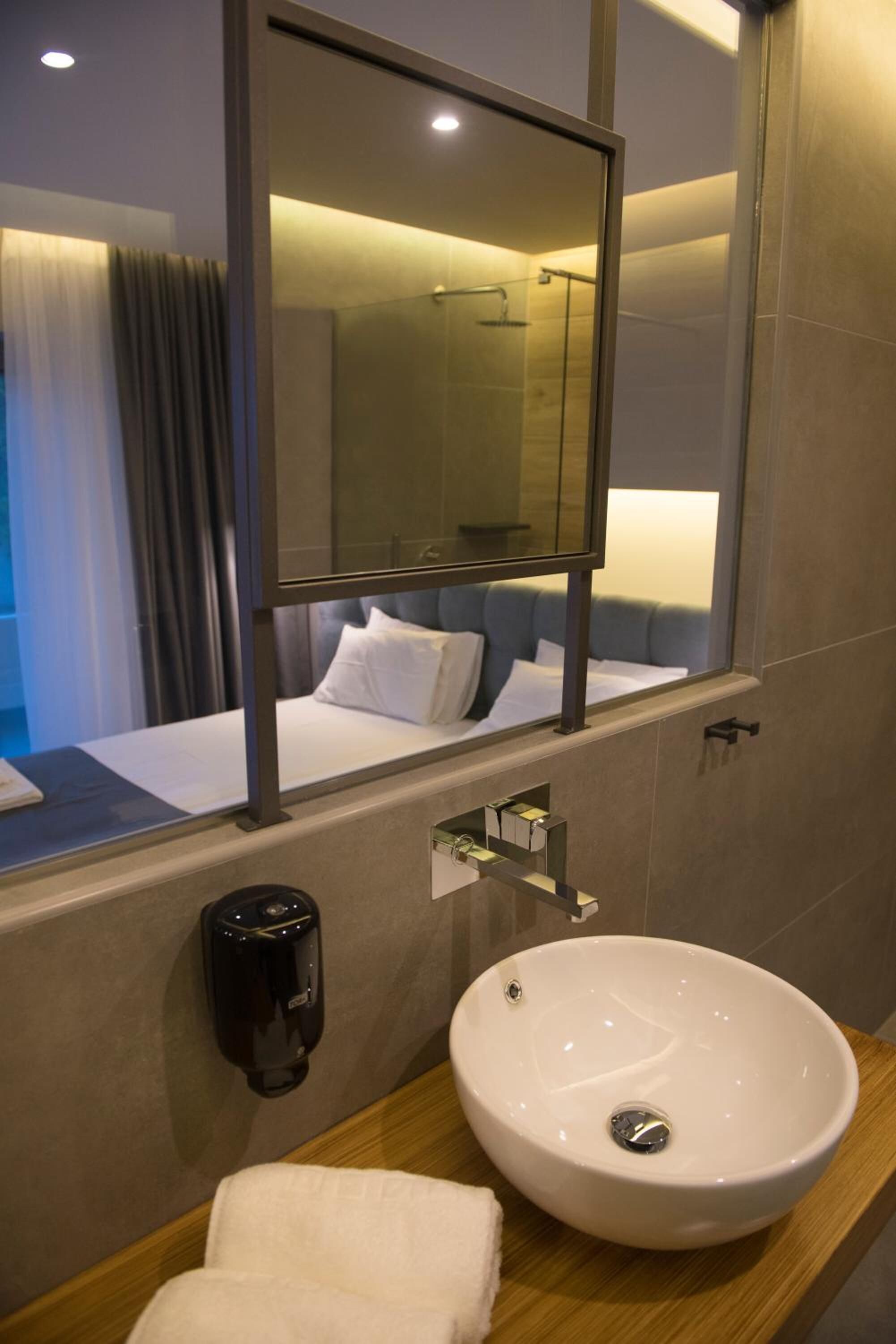 Een hotelbadkamer met een grote spiegel, een witte wastafel, een handdoek en een douche.