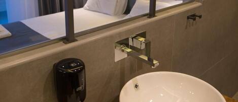 Een hotelbadkamer met een grote spiegel, een witte wastafel, een handdoek en een douche.