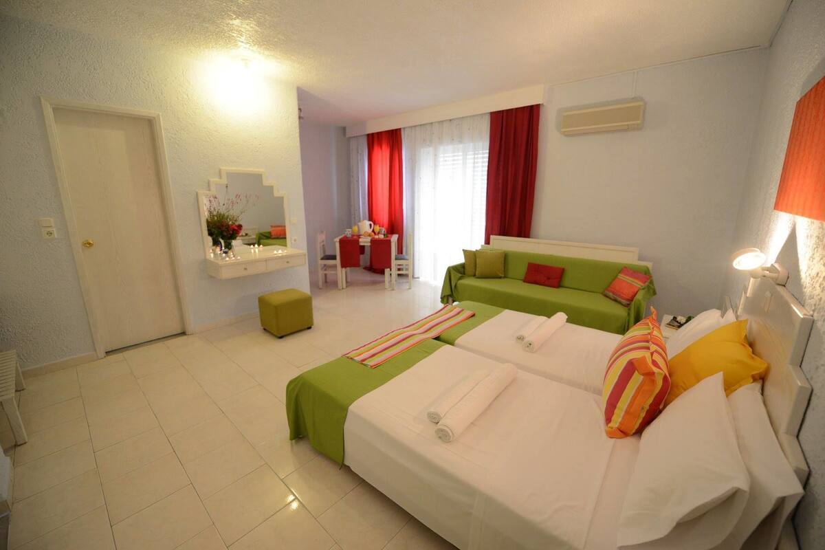 A hotel room with a bed, a desk, a chair, and a small table with a red tablecloth.