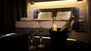 Una habitación con una cama, una mesita de noche y una mesa con dos copas y una botella de champán en un cubo.