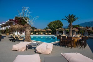 A poolside area with lounge chairs, a bar, and a view of mountains. - Golden Star (Kos)