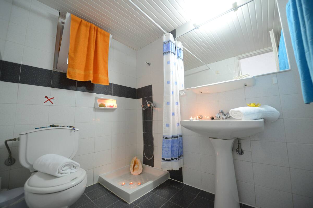 A bathroom with a toilet, a sink, a shower with a curtain, and a towel rack.