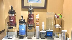 A coffee station with various drink dispensers, including options for decaf, regular, and hot water. - Comfort Inn & Suites Airport North (Calgary)