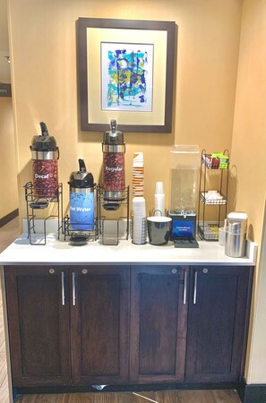 A coffee station with various drink dispensers, including options for decaf, regular, and hot water. - Comfort Inn & Suites Airport North (Calgary)