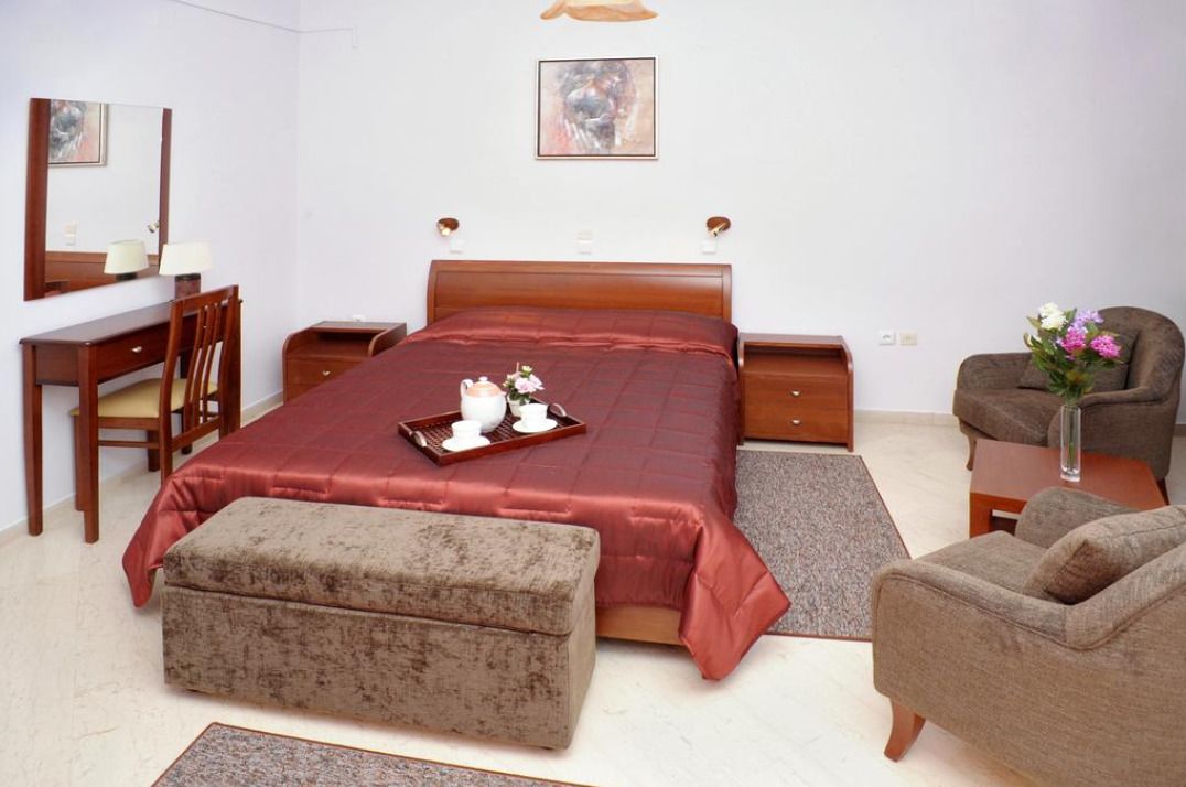 A bedroom with a bed, a desk, a chair, a sofa, and a nightstand.