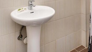 A bathroom with a white sink, a mirror, and a shower area. - Villa Plaza (Spetses)