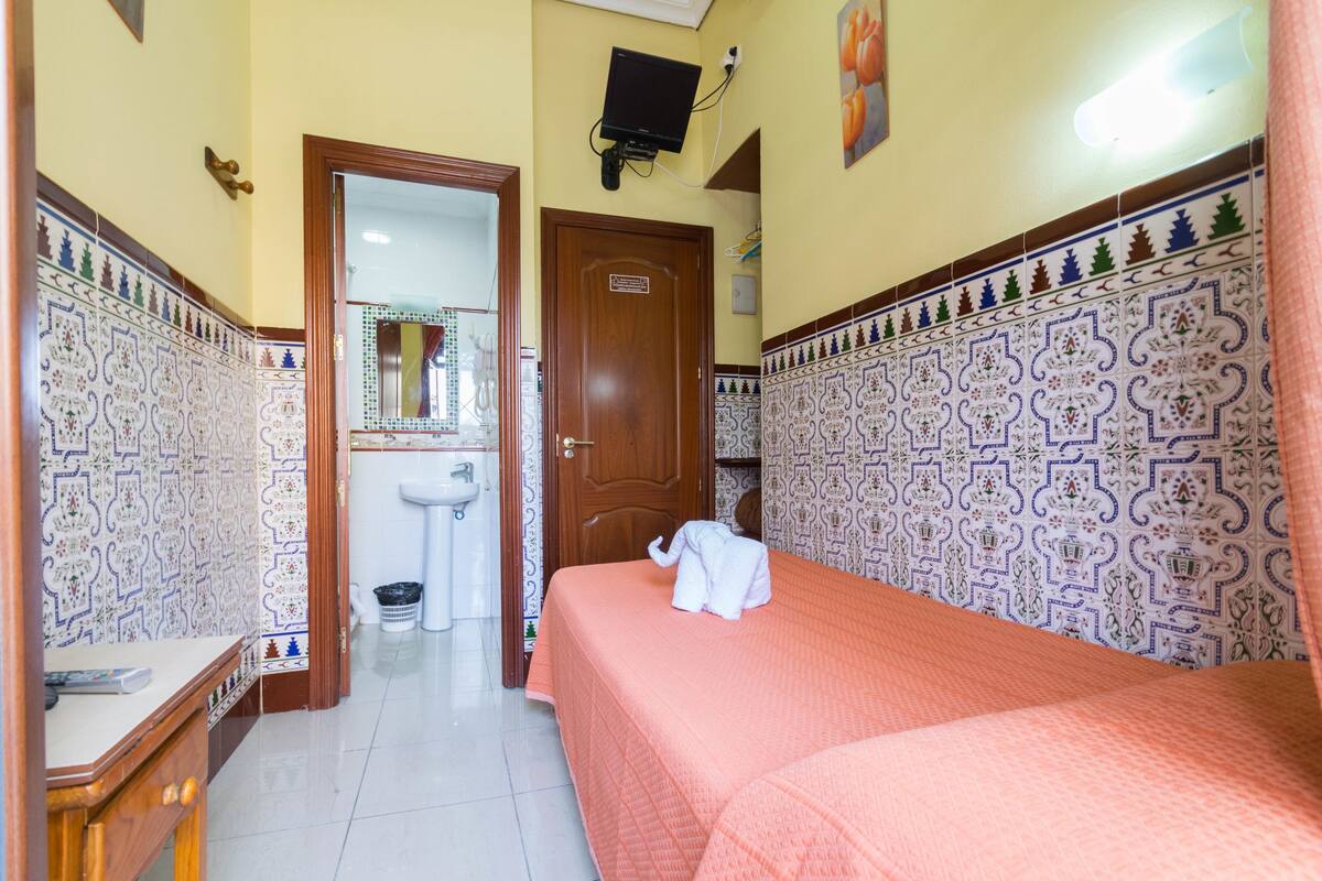 Una habitación de hotel con una cama, un tocador de madera, un lavabo y un espejo.