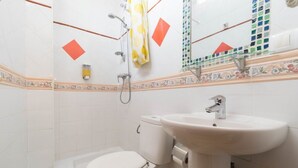 Une salle de bain avec des toilettes, un lavabo et une douche.