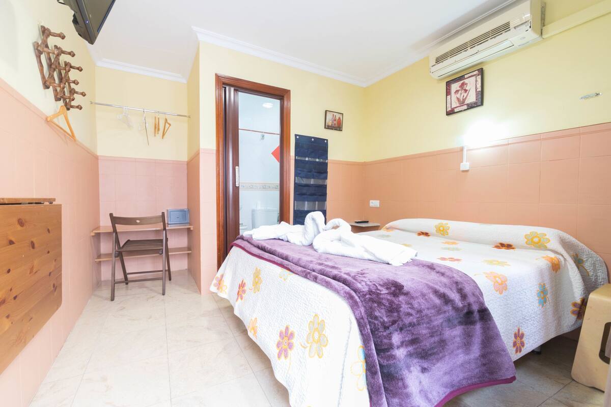 Una habitación de hotel con una cama, una silla, un escritorio y un armario.