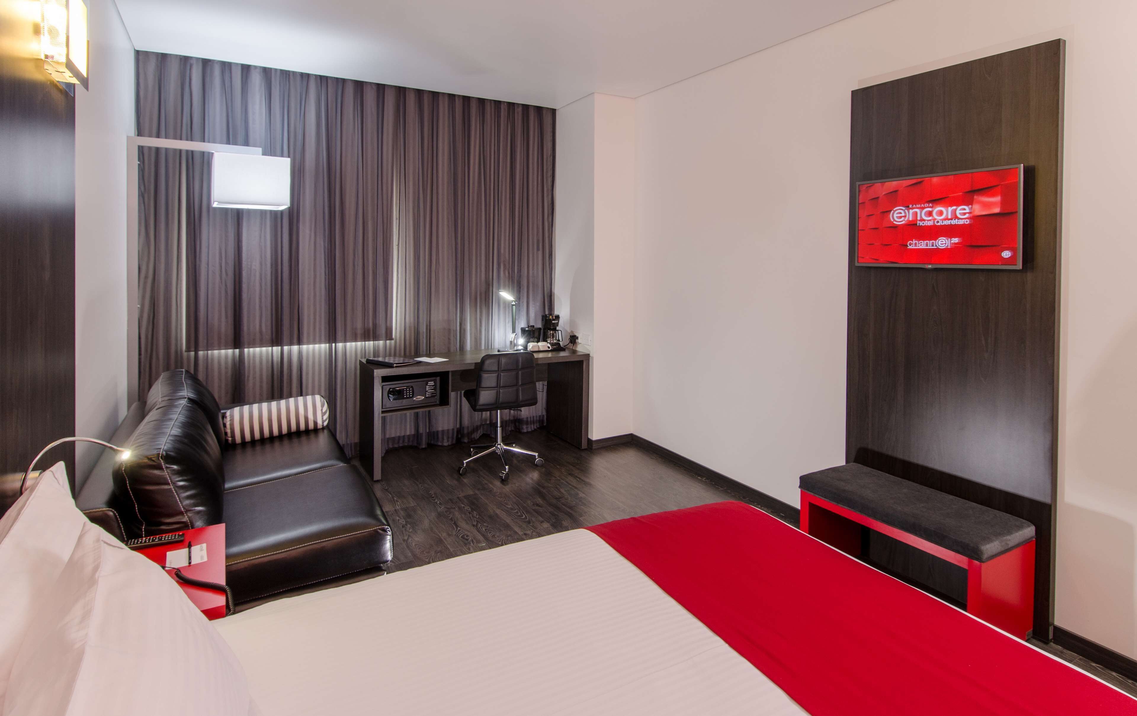 Una habitación de hotel con cama, escritorio, silla, sofá y televisión.