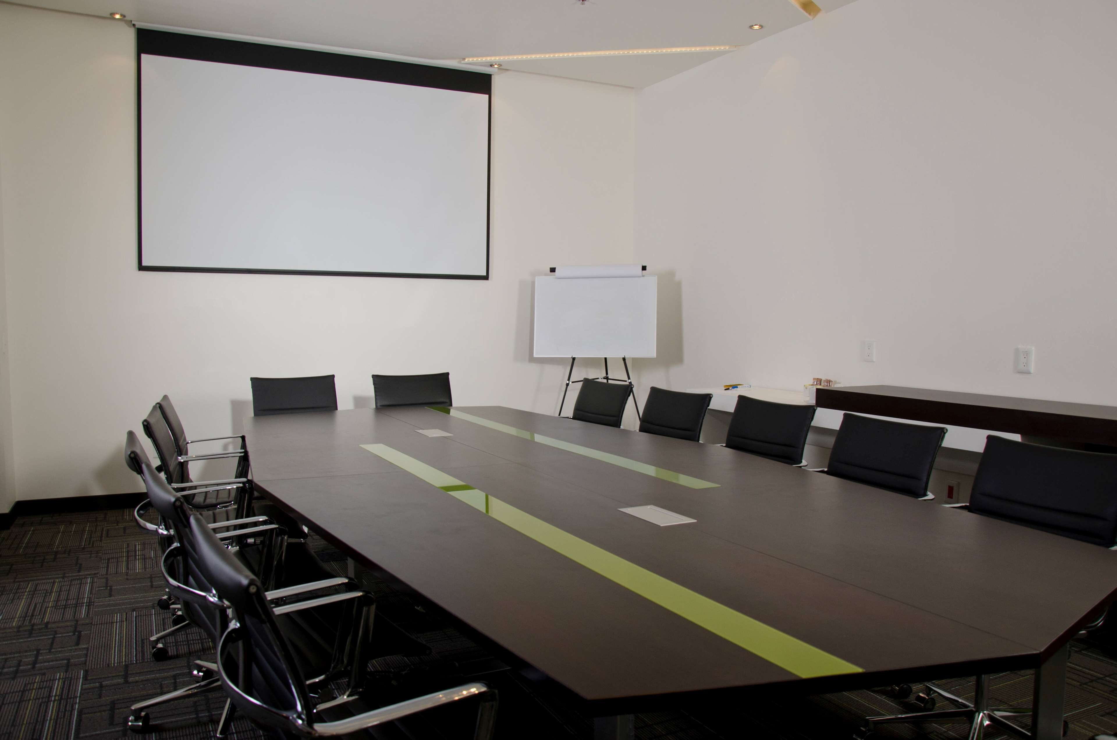 A conference room with a long table, chairs, a projector screen, and a whiteboard.