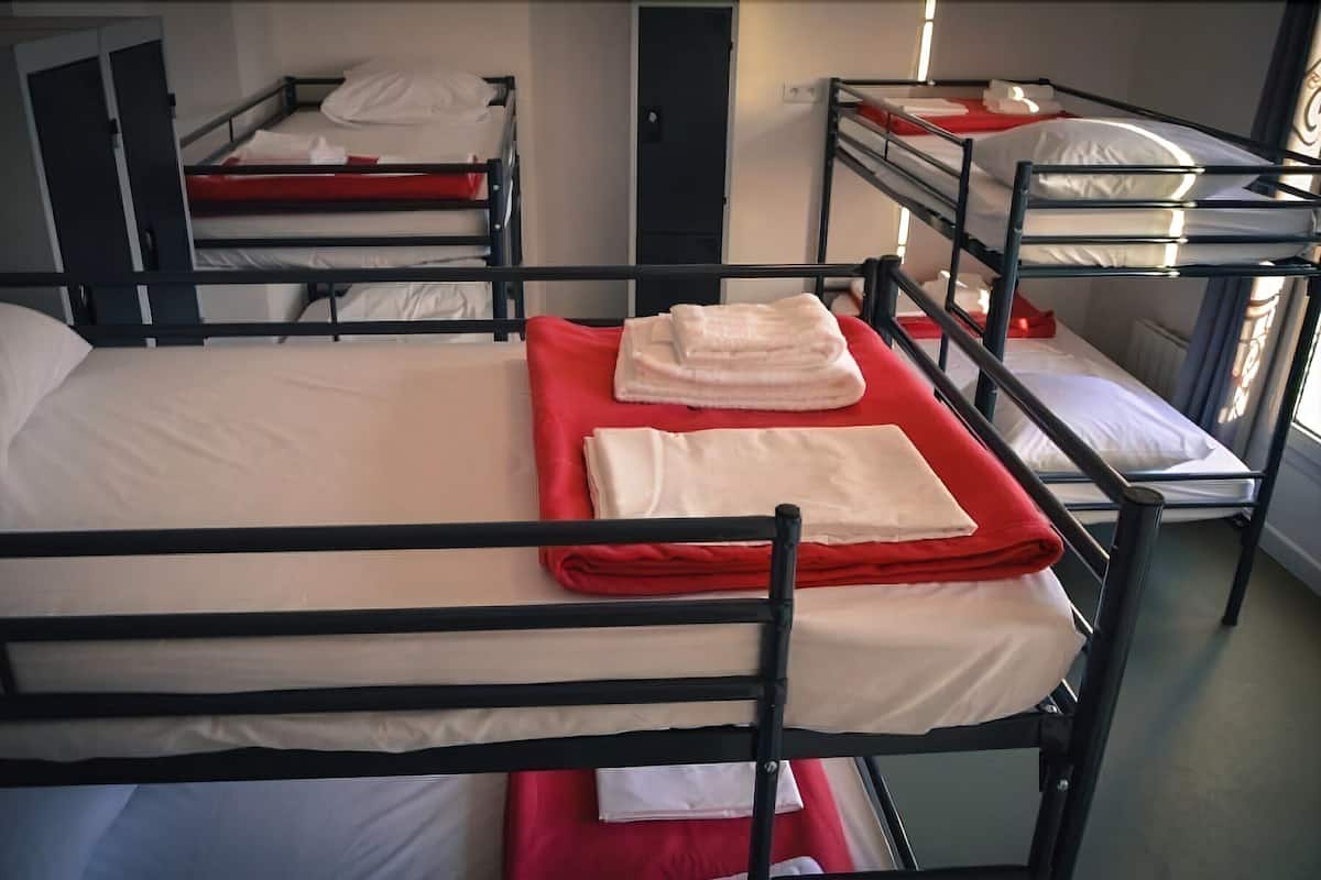 A bunk bed room with white bedding and red blankets.