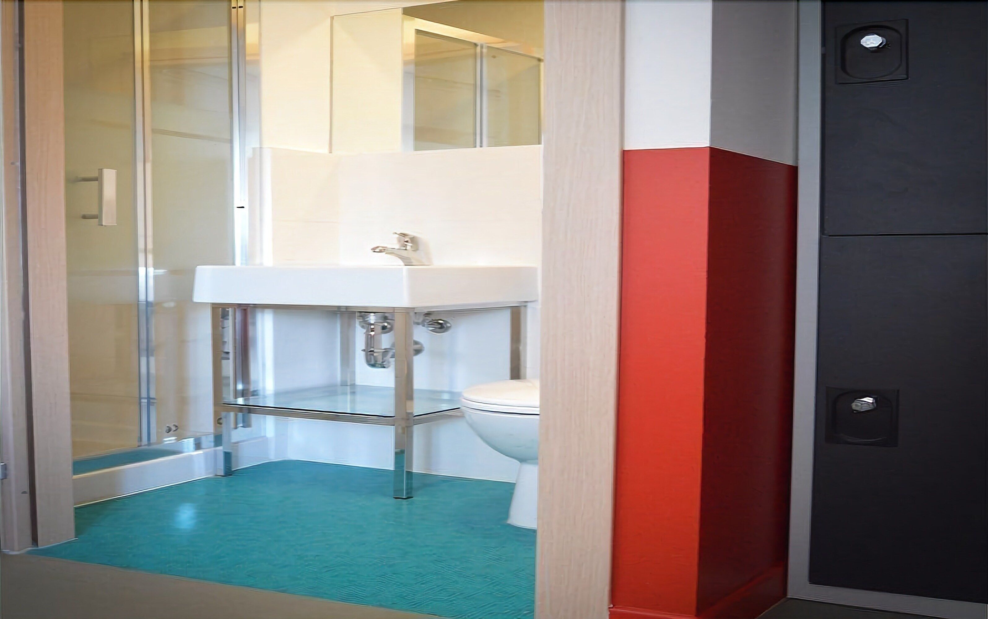 A bathroom with a glass shower enclosure, a white sink, and a toilet.
