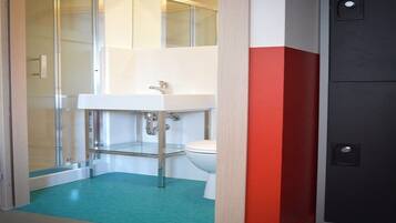 A bathroom with a glass shower enclosure, a white sink, and a toilet.