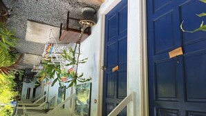 A staircase leading to a blue door with a nameplate, surrounded by plants and a textured ceiling. - The Box Chalet (Langkawi)