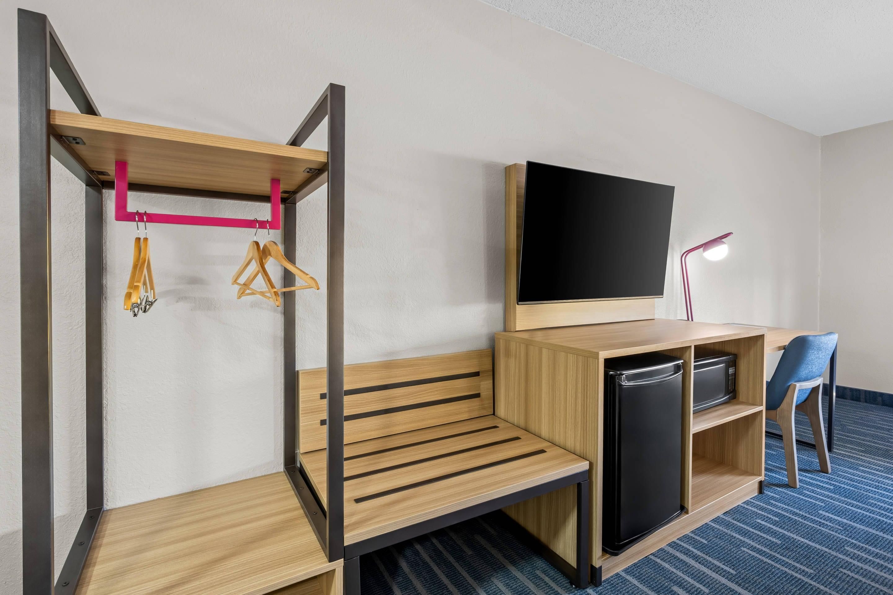Habitación de hotel con literas, televisor de pantalla plana, escritorio con computadora, microondas y una silla.