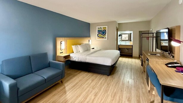 A hotel room with a bed, a sofa, a desk, and a mirror. - Park Inn by Radisson, Weldon - Roanoke Rapids (Weldon)