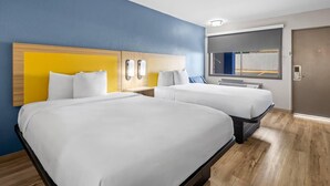 A hotel room with two beds, a wooden headboard, a nightstand, and a window with a view of a fence. - Park Inn by Radisson, Weldon - Roanoke Rapids (Weldon)