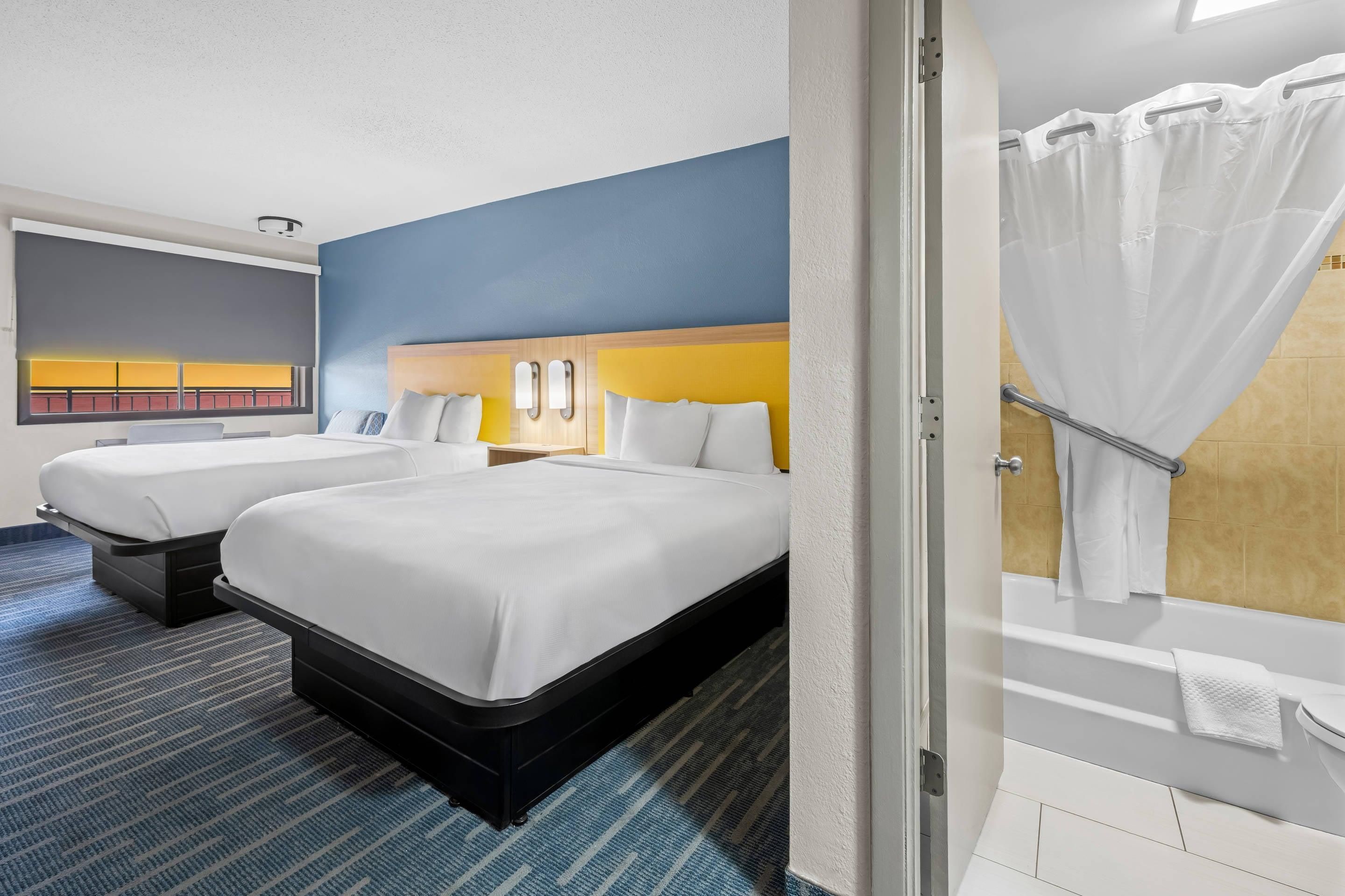 Une chambre d’hôtel avec deux lits, une salle de bain et une vue sur le paysage urbain.