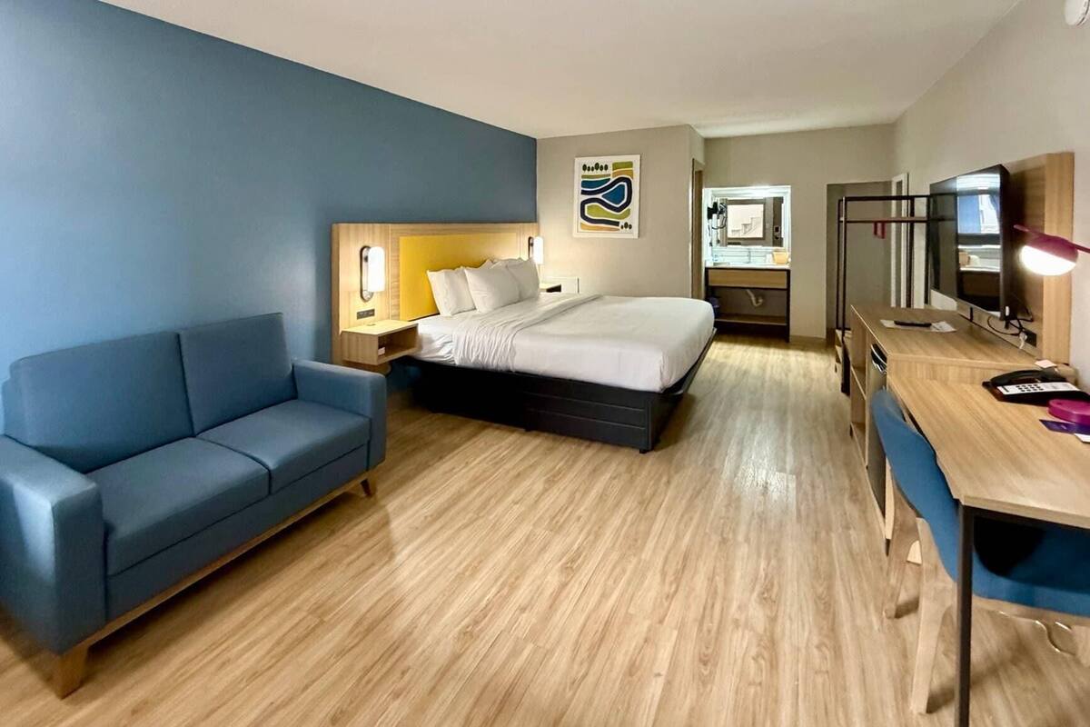 Una habitación de hotel con cama, sofá, escritorio y espejo.