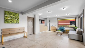 A modern living room with a bench, a sofa, a coffee table, and a view of the outside. - Park Inn by Radisson, Weldon - Roanoke Rapids (Weldon)