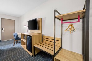 A hotel room with a bunk bed, a desk with a flat-screen TV, a chair, and a small refrigerator. - Park Inn by Radisson, Weldon - Roanoke Rapids (Weldon)